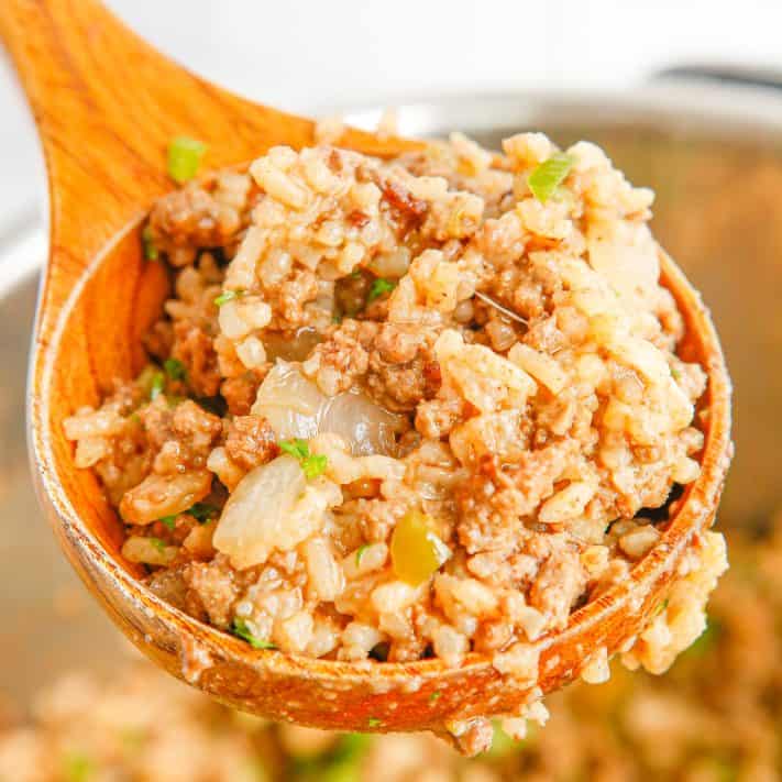 Square image of wooden spoon with some Instant Pot Dirty Rice in it.