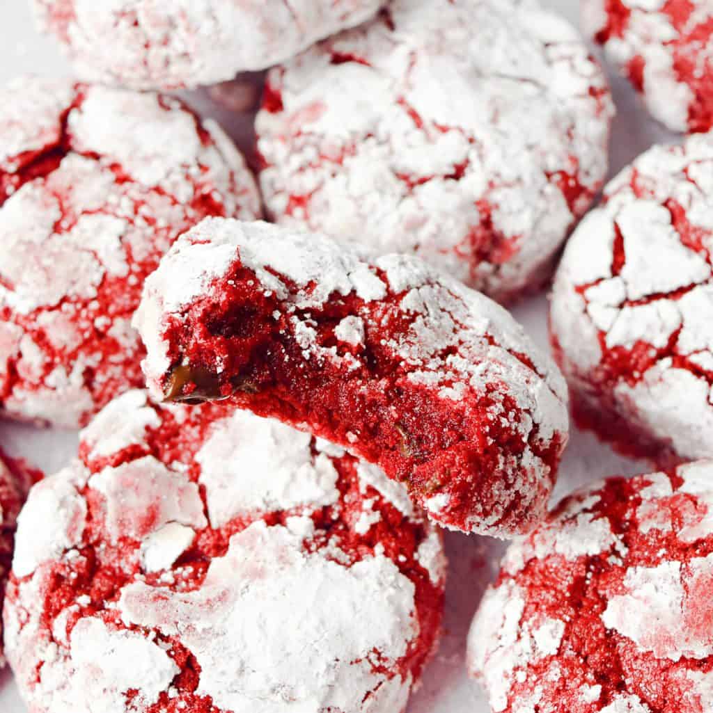 Square image of stacked Red Velvet Crinkle Cookies with bite taken out of one.
