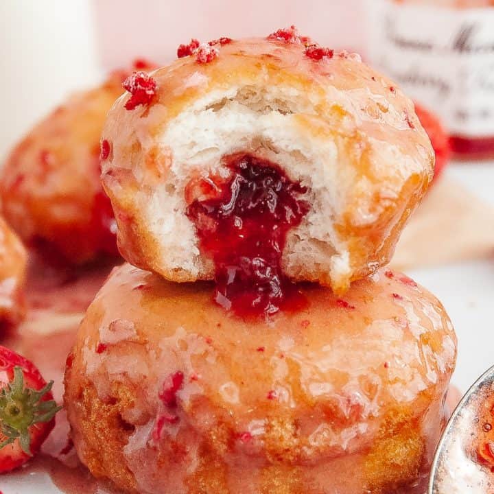 Square image of finished Strawberry Jelly Filled Biscuit Donuts with bite taken out of one.