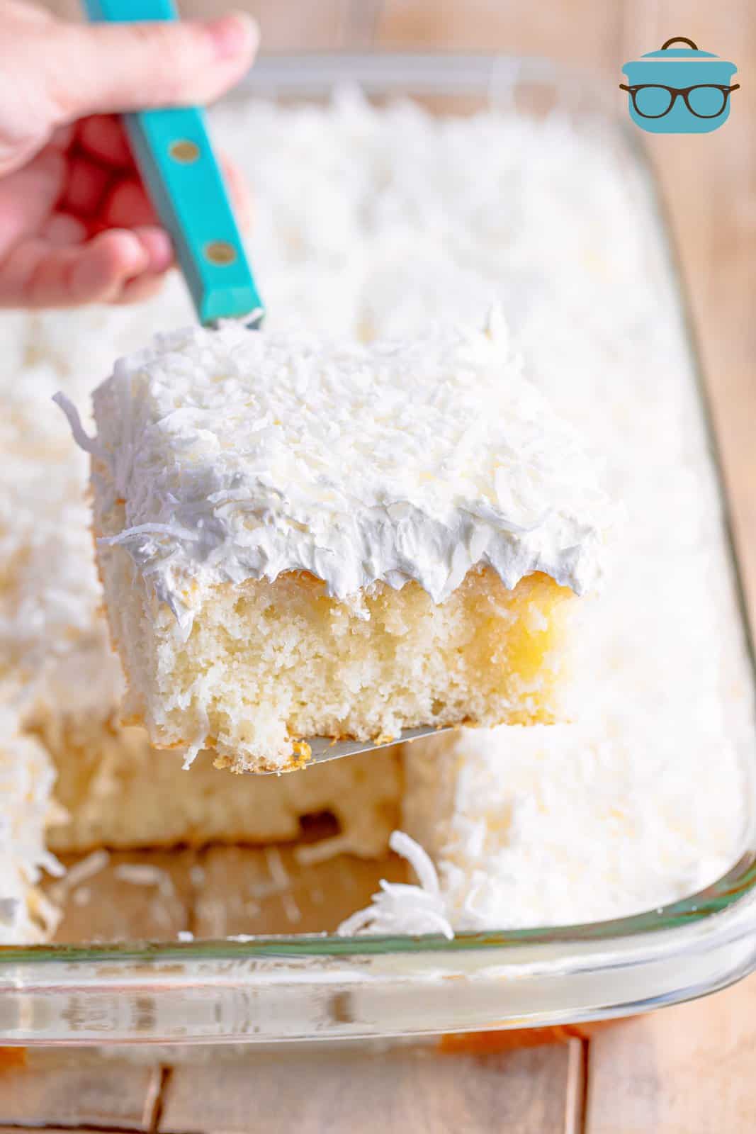 a spatula lifting out a piece of coconut cake from a baking pan.