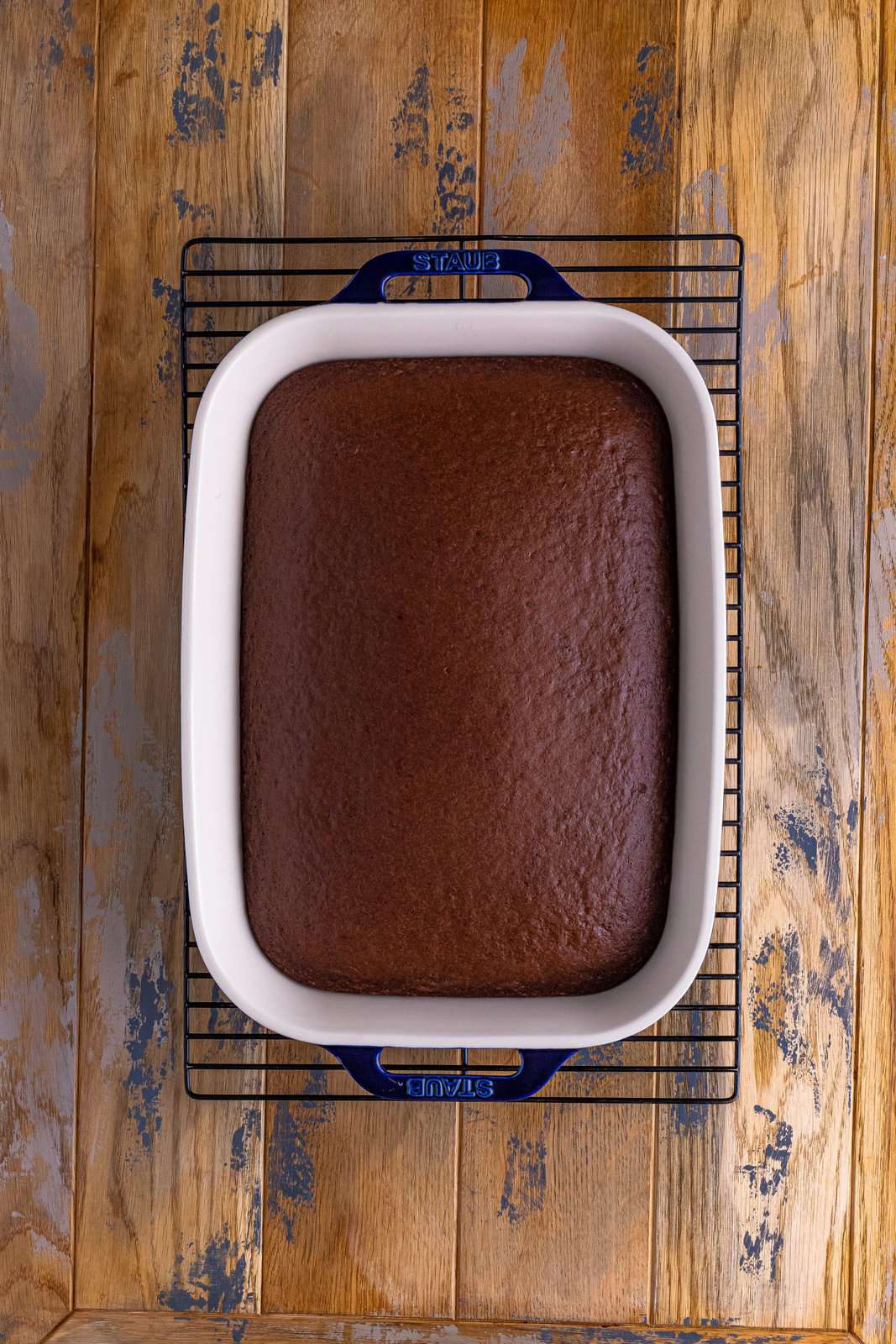 fully baked chocolate cake in a baking dish on a wire cooling rack.