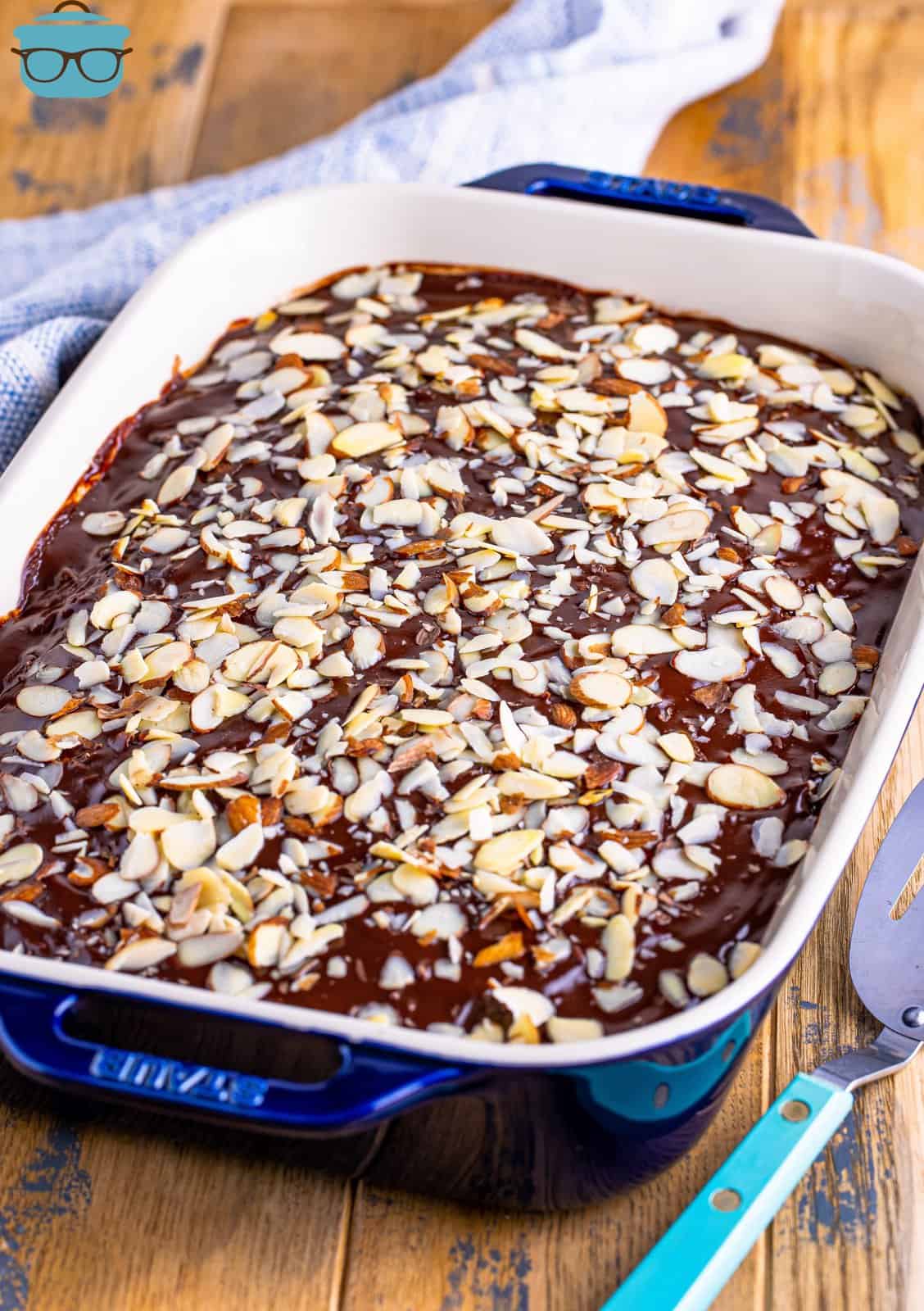 sliced almonds shown evenly sprinkled on top of chocolate cake in baking dish. 