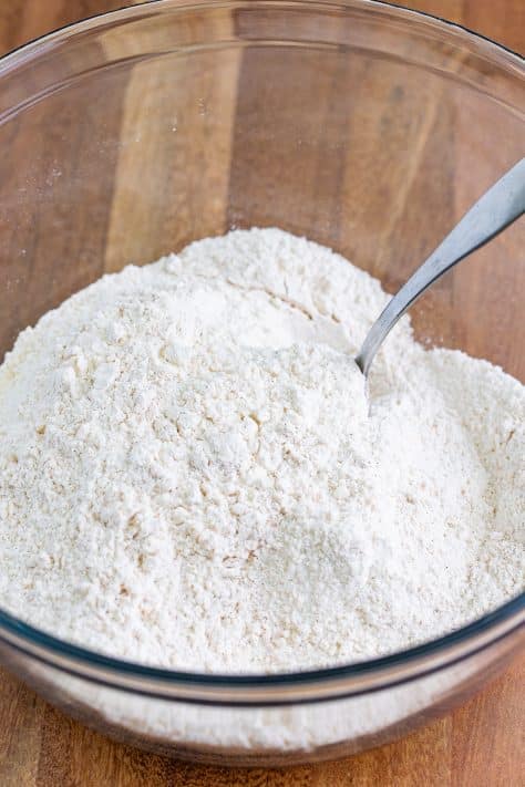 A mixing bowl with flour, sugar, baking powder, baking soda, cinnamon, and salt.