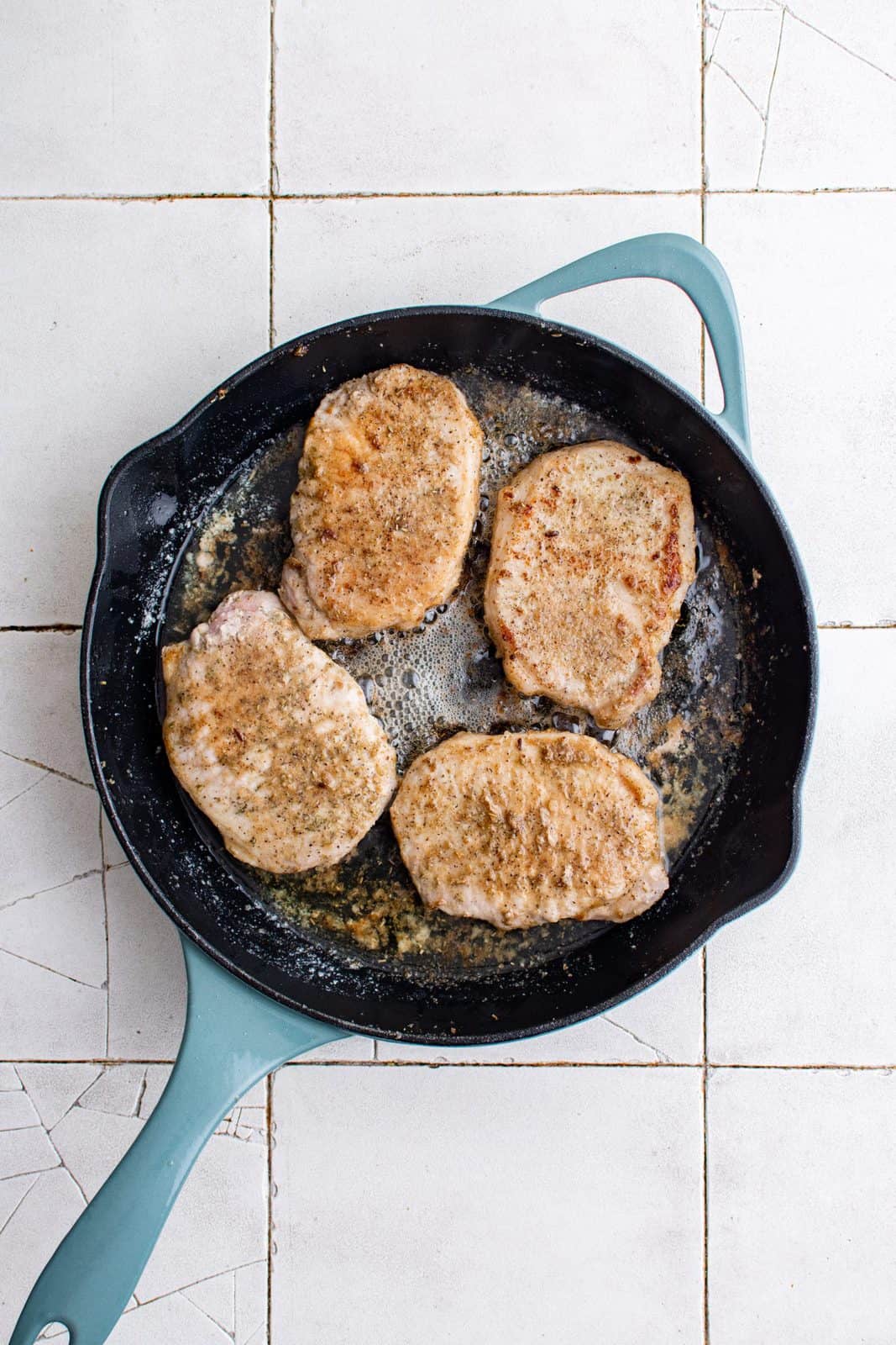Flipped over pork chops in pan showing browning.