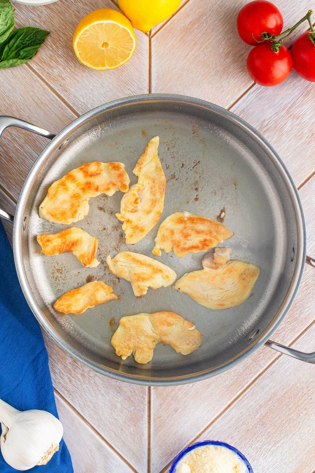 Chicken pieces being browned with olive oil in pan.