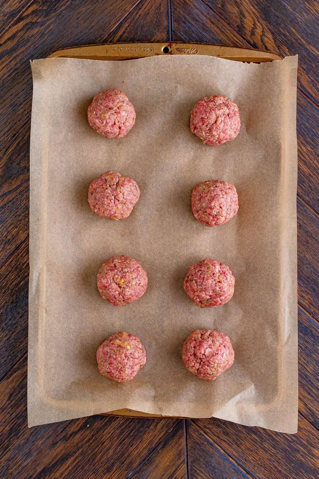 Meat mixture rolled into meatballs and placed on parchment lined baking sheet.