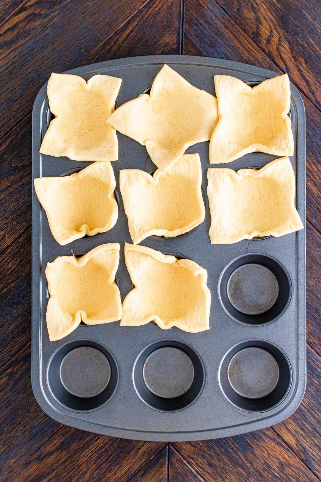 Crescent dough sheet cut into squares and pressed into muffin tin.