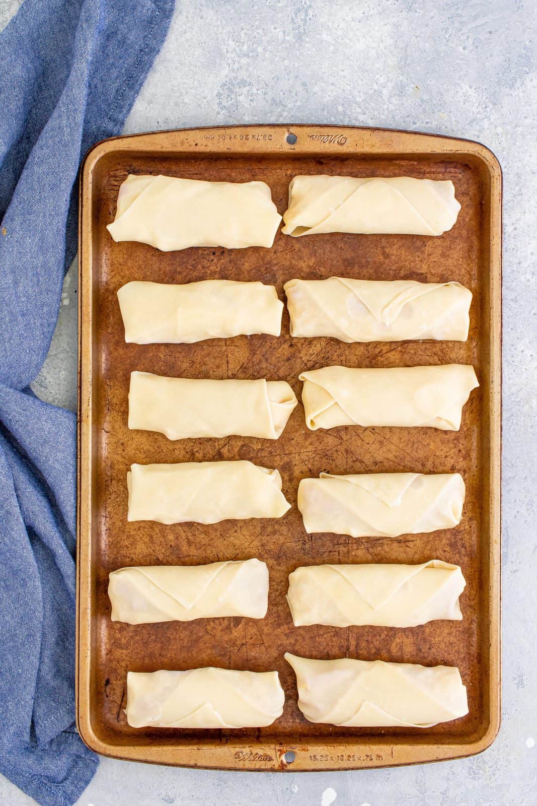Rolled egg rolls on baking pan.