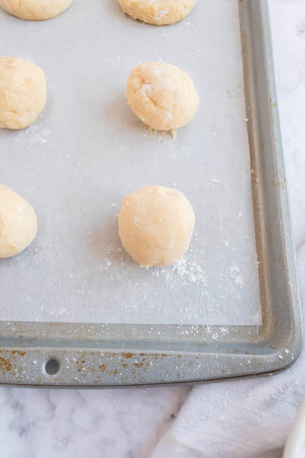 Cookie dough rolled into balls and placed on parchment line baking sheet.
