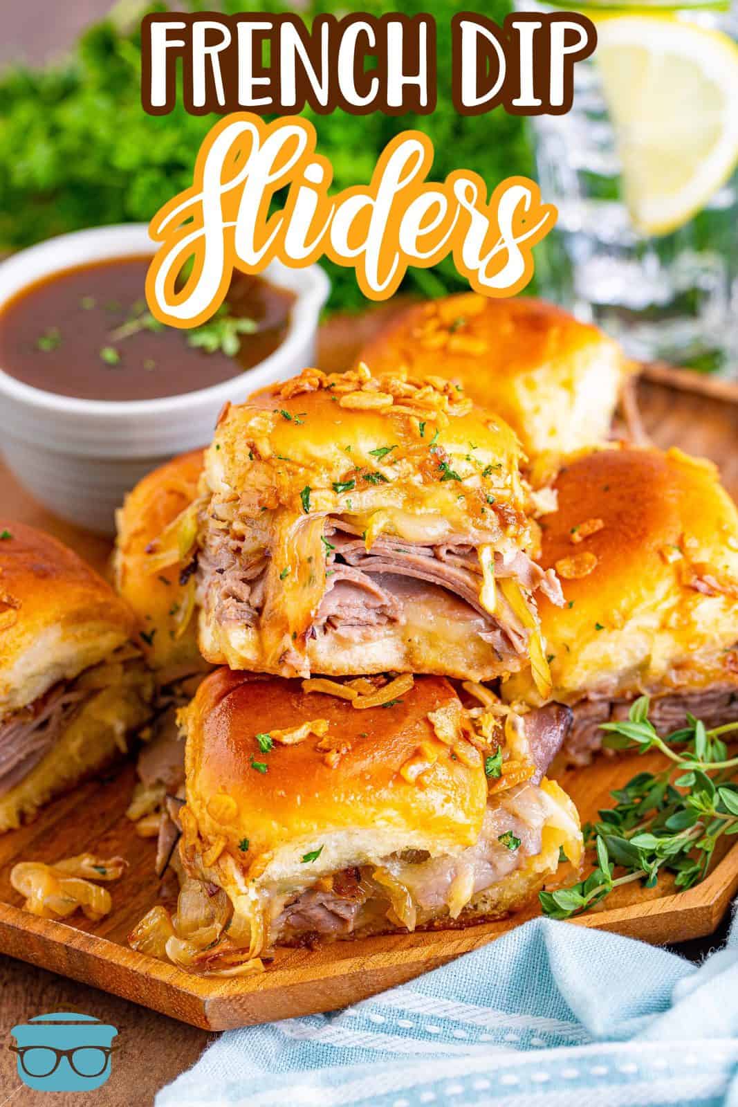 Pinterest image of French Dip Sliders stacked on top of one another on wooden plate.