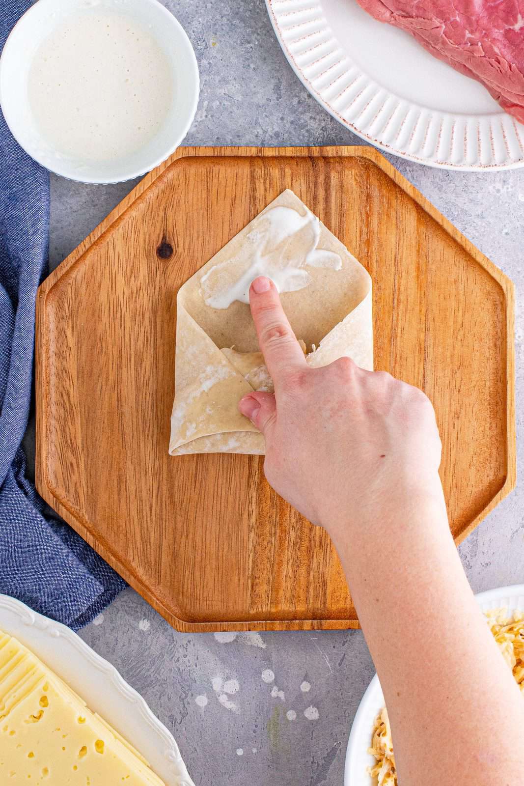 Finger rubbing egg roll wrapper with flour and water mixture.