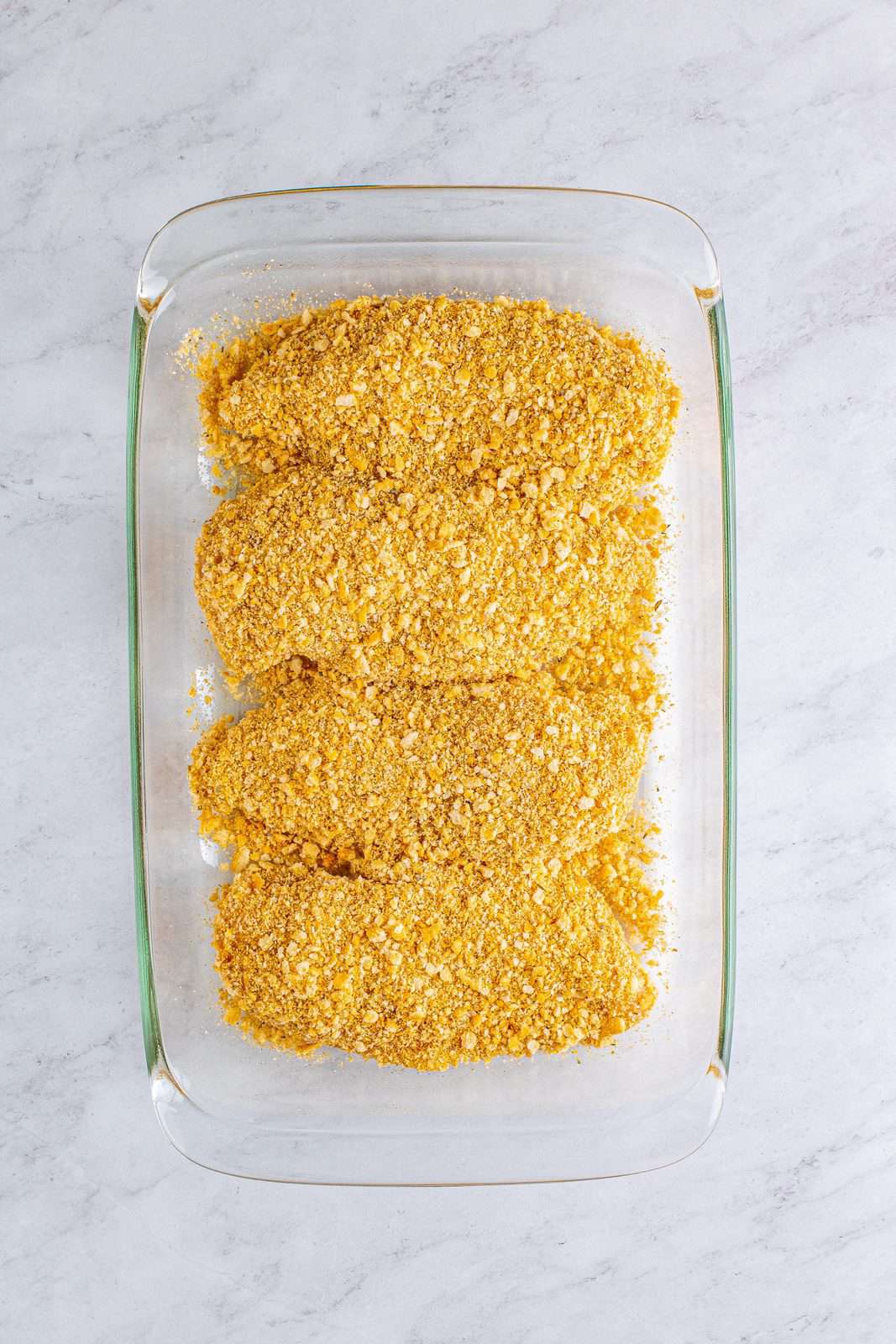 Chicken added to baking dish with extra cracker mixture.