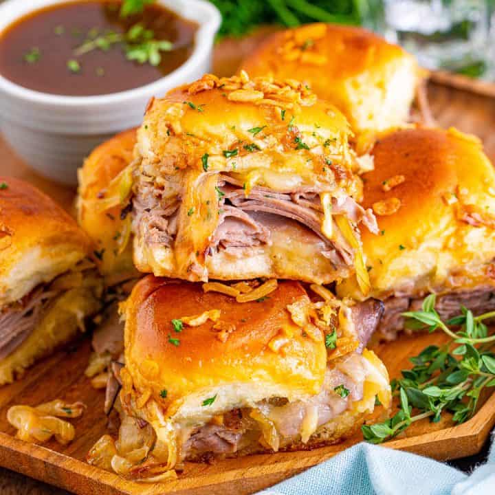 Square image of stacked French Dip Sliders on wooden plate.