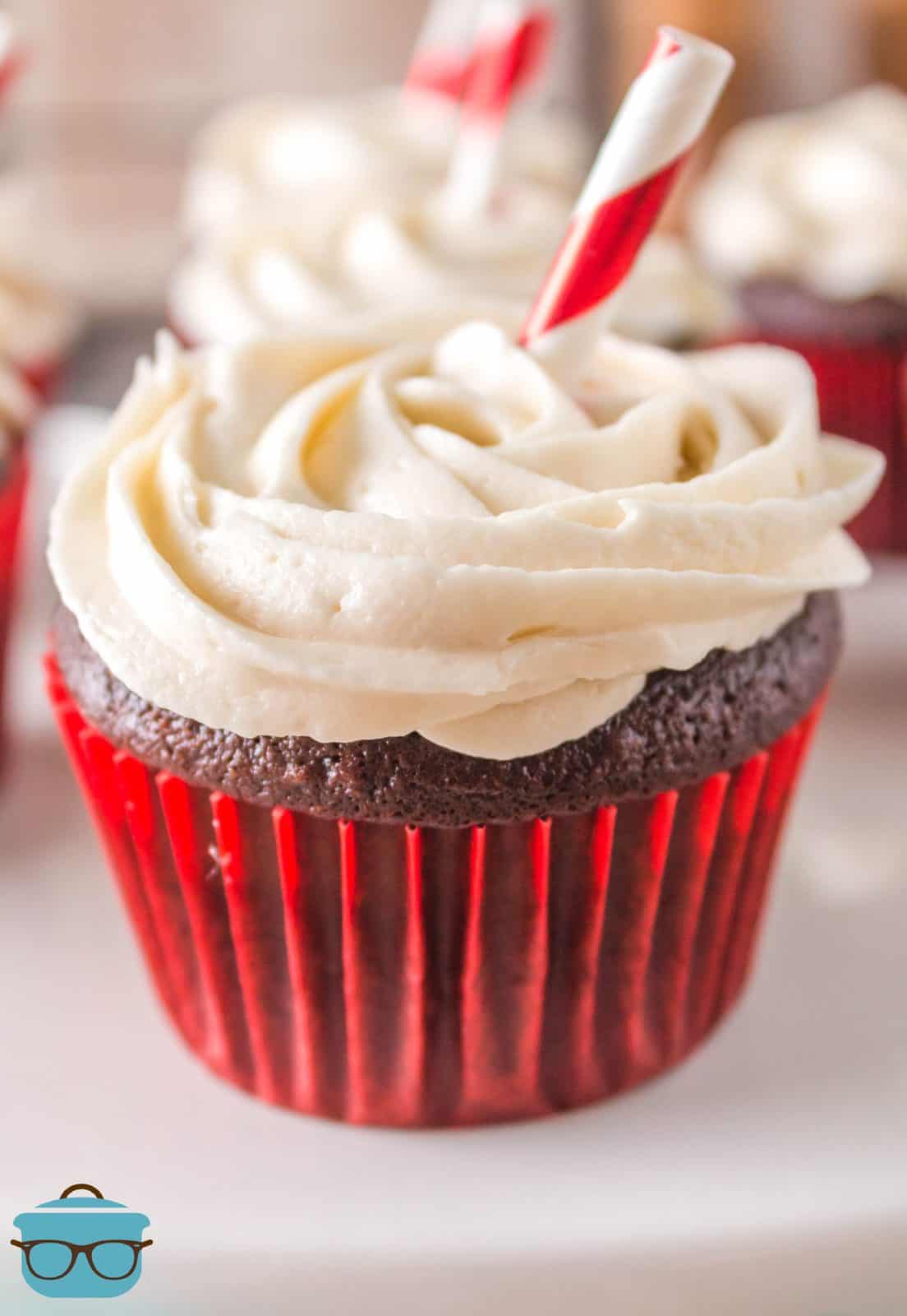 One Coca Cola Cupcake with swirled red and white straw inserted into it.