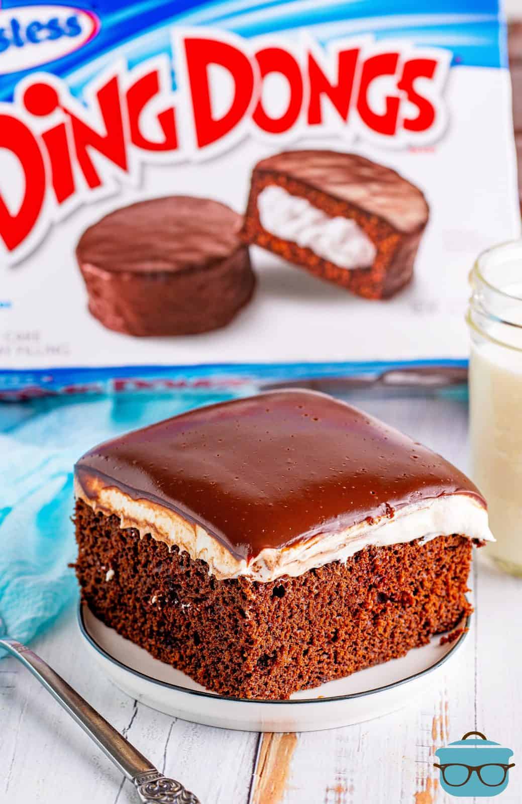 Slice of Ding Dong Cake on white plate in front of a box of Ding Dongs.