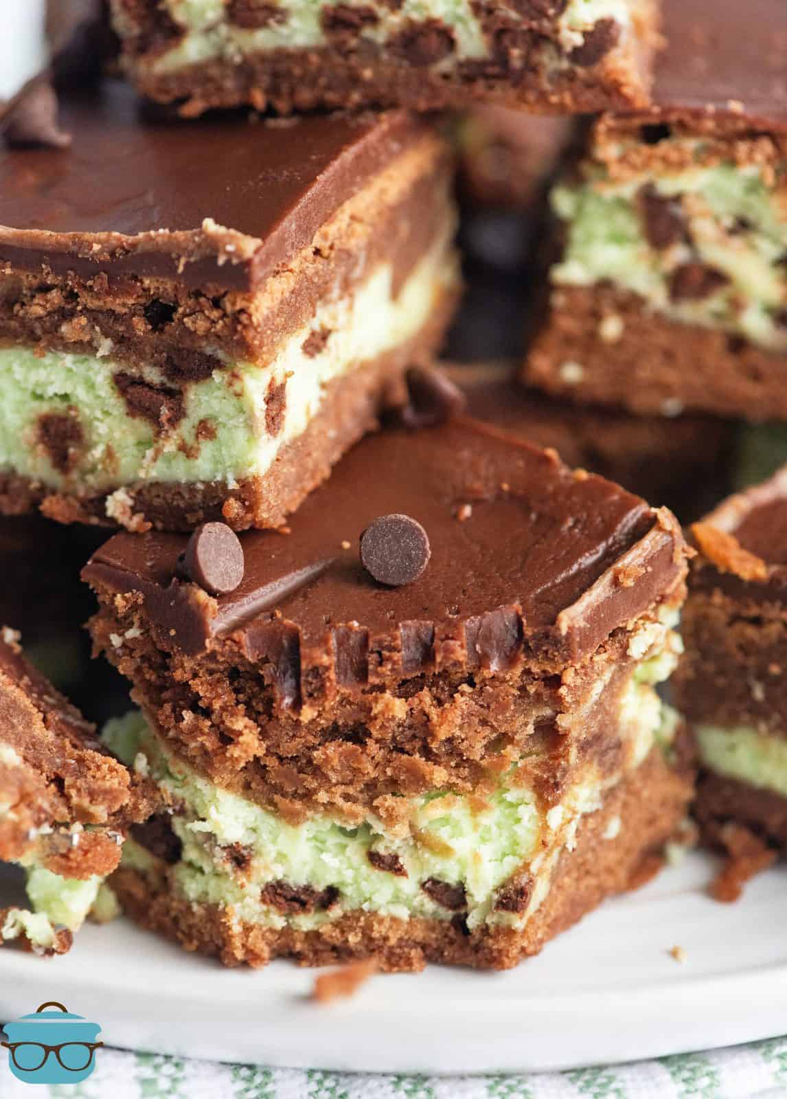 Close up of stacked Mint Cream Cheese Brownies on white plate.