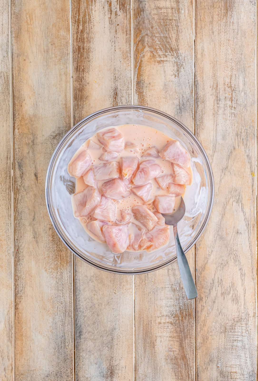 diced chicken meat showing in buttermilk brine in a clear bowl. 