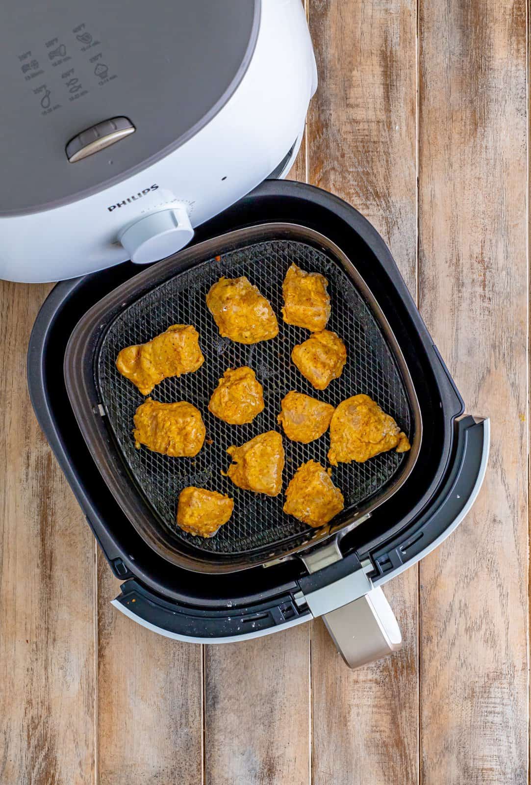 coated chicken breasts shown in an air fryer. 