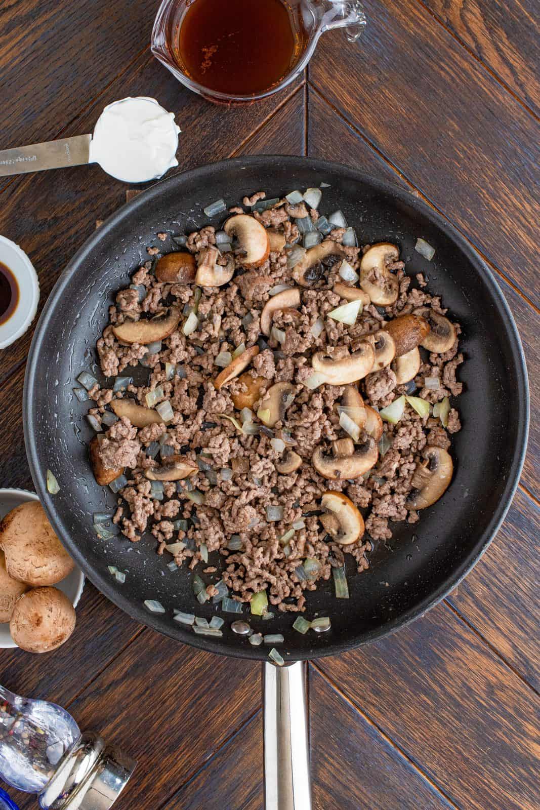 Ground beef, mushrooms, onion, and garlic sauteed in pan.