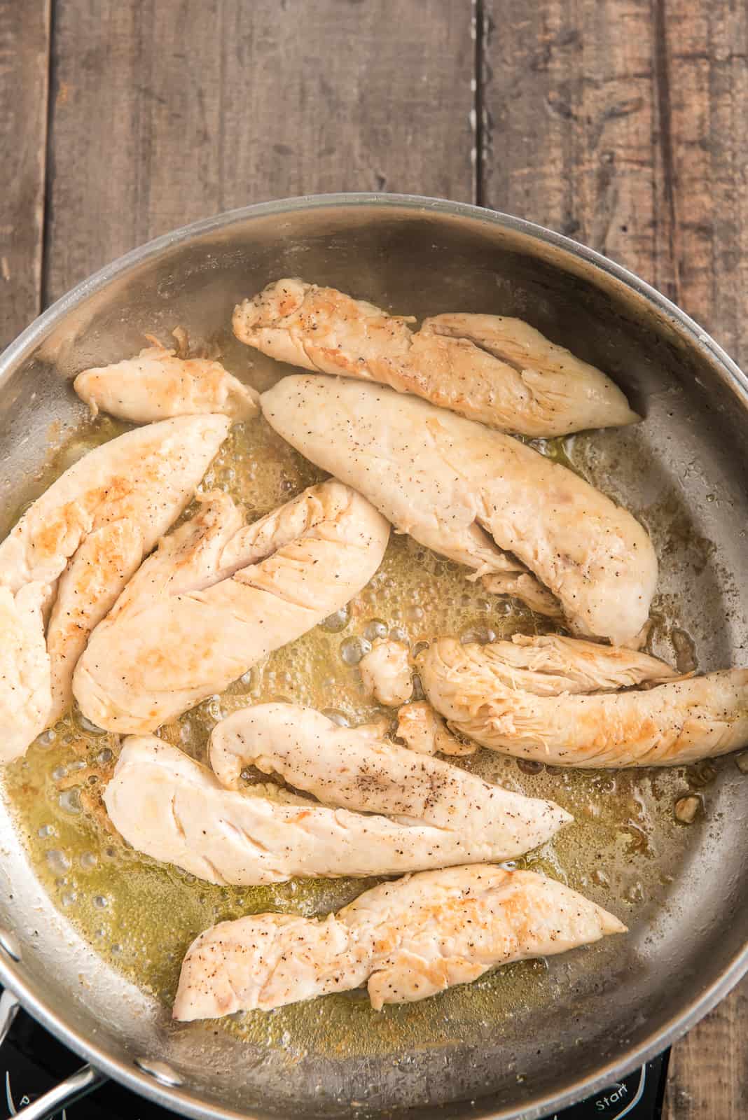 Chicken tenderloins cooking in pan.