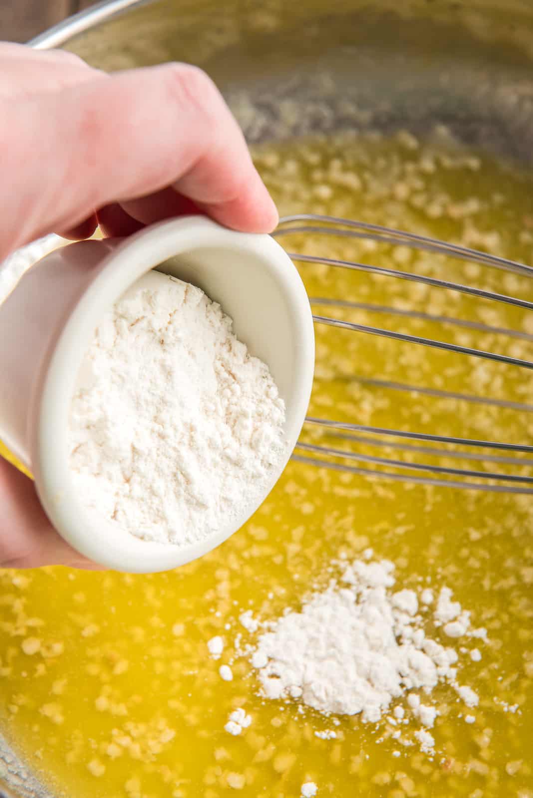 Flour being added to melted butter and garlic.