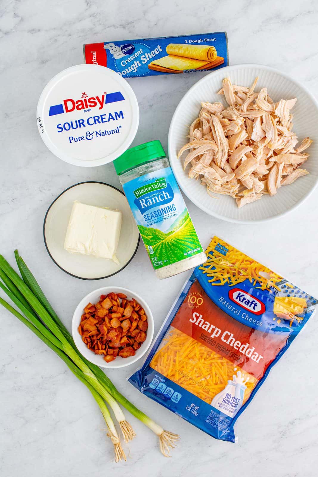 Ingredients needed: cream cheese, sour cream, dried ranch seasoning, cooked chicken, shredded cheddar cheese, bacon, scallion, crescent dough sheet and ranch dressing.