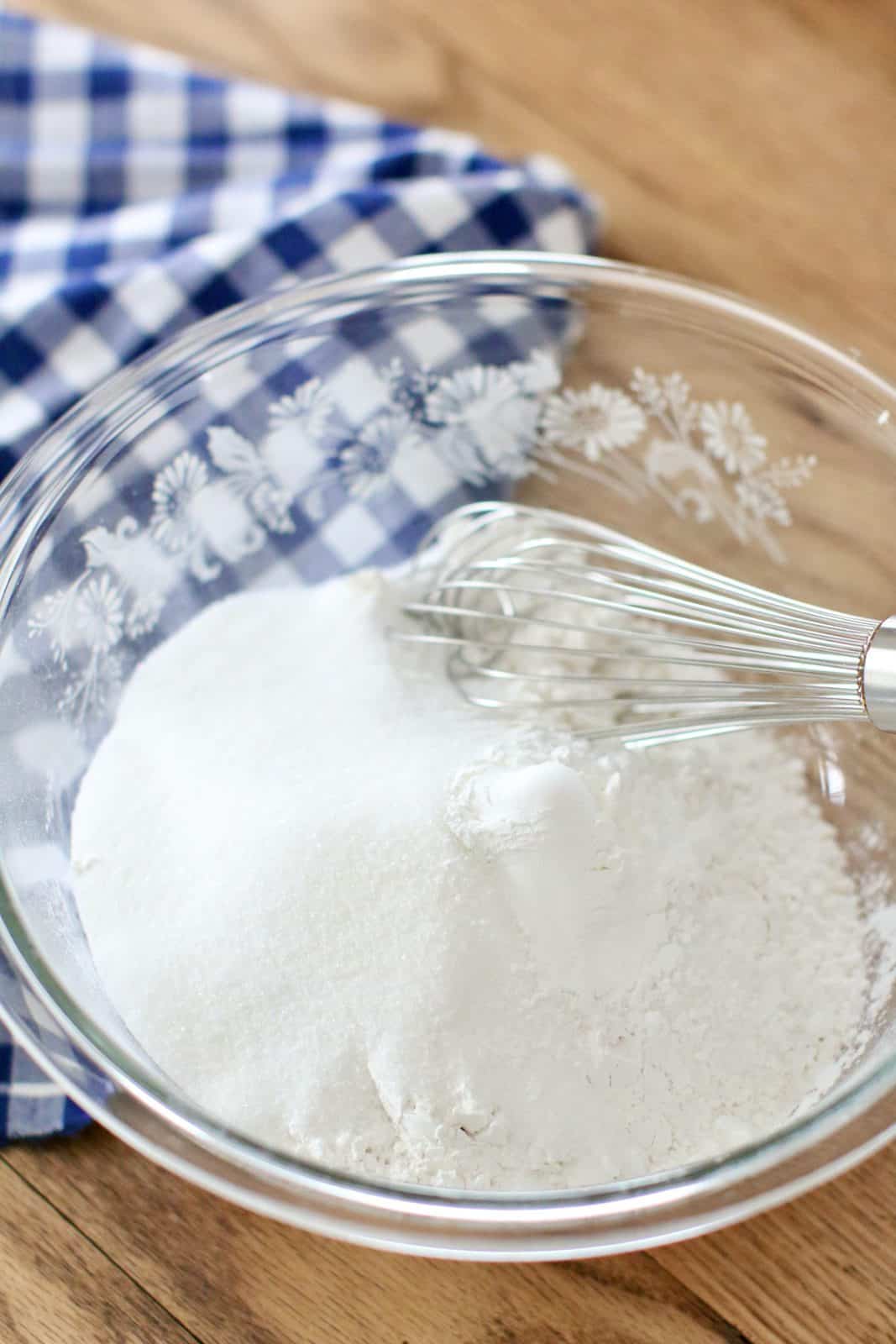 flour, sugar, baking powder and salt in a glass bowl with a metal whisk.