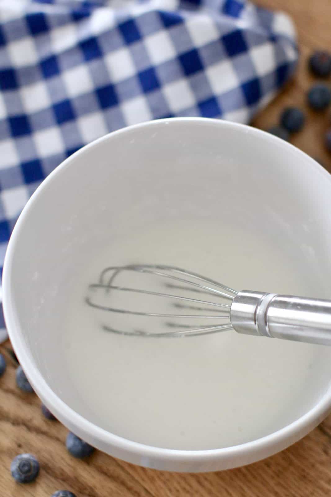 powdered sugar and milk whisked together in a small, white bowl.