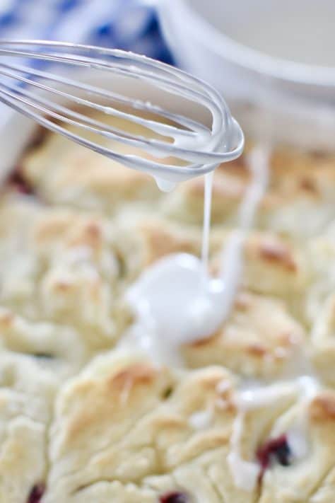 powdered sugar icing drizzled on top of baked biscuits with a whisk.