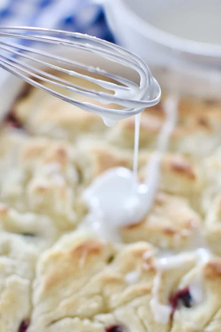 powdered sugar icing drizzled on top of baked biscuits with a whisk.