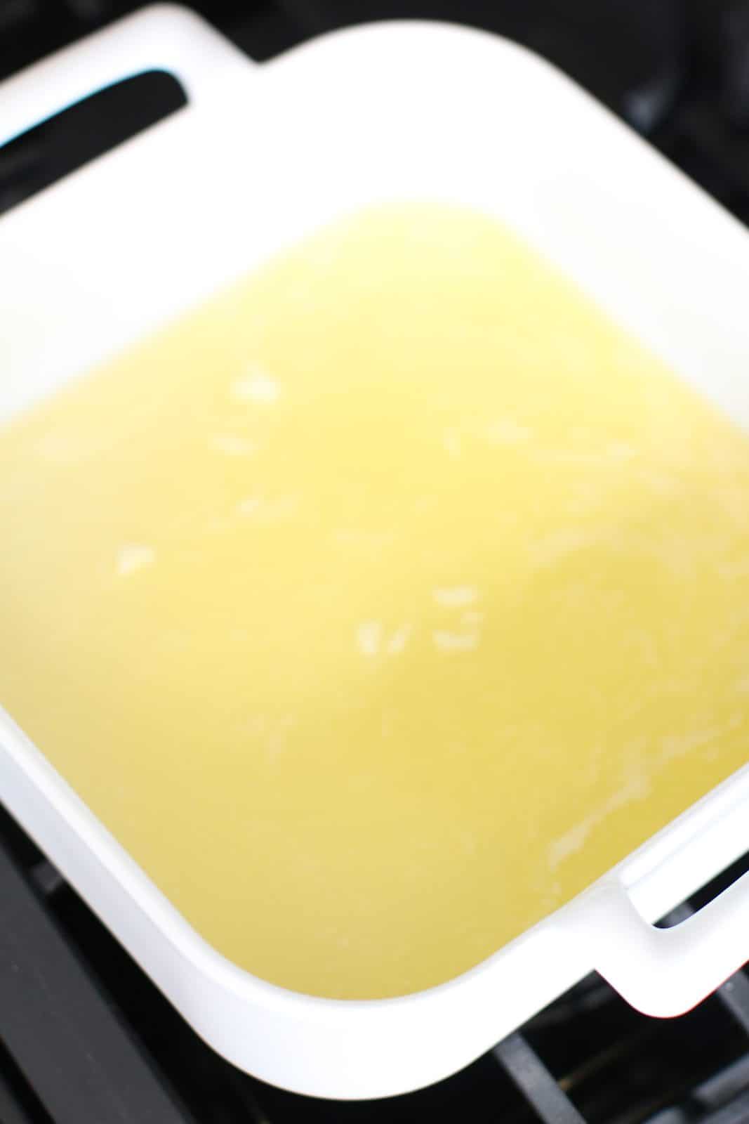 melted butter in a white square baking dish with handles.