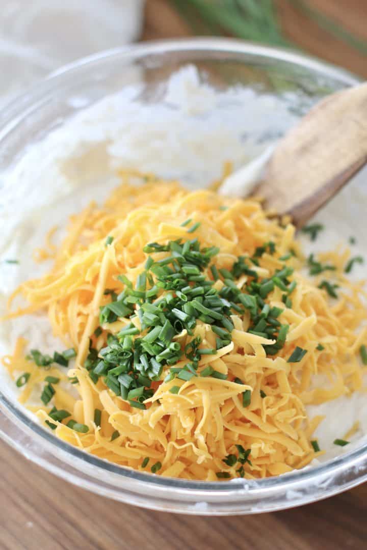 shredded cheddar and chopped chives in a glass bowl.