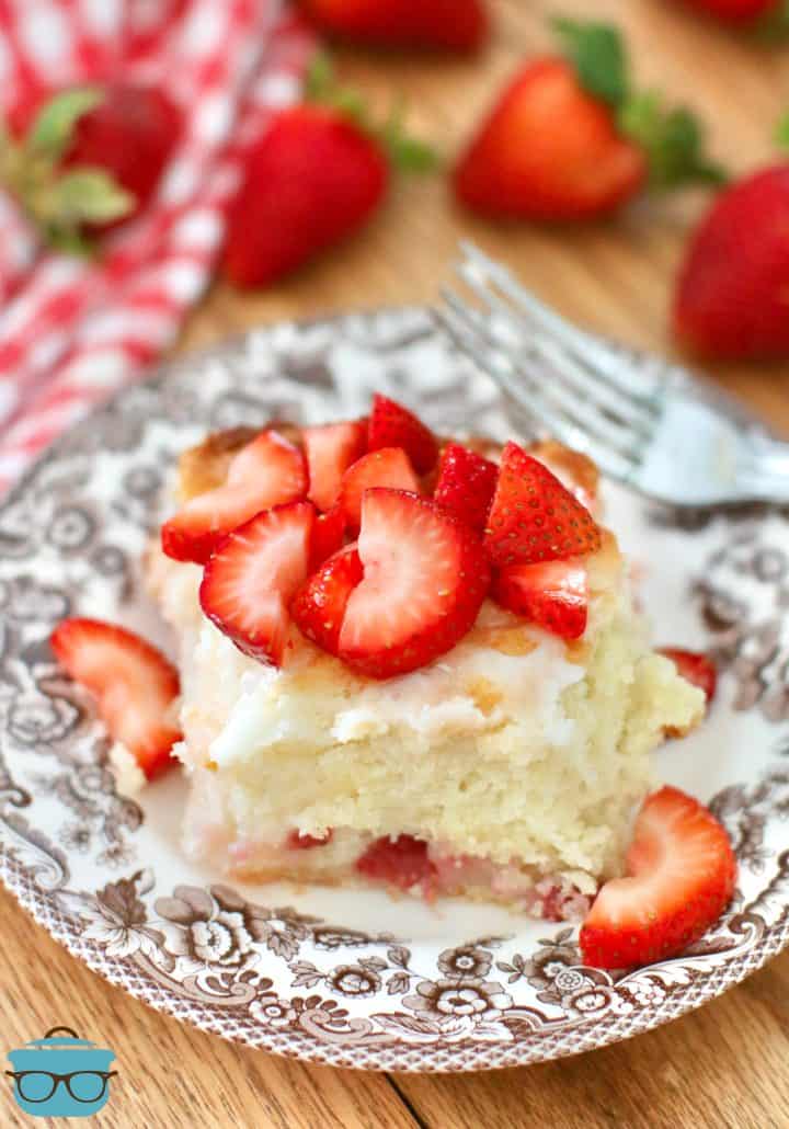 Strawberry Butter Biscuit on a brown and white plate with sliced strawberries on top and a fork on the side.
