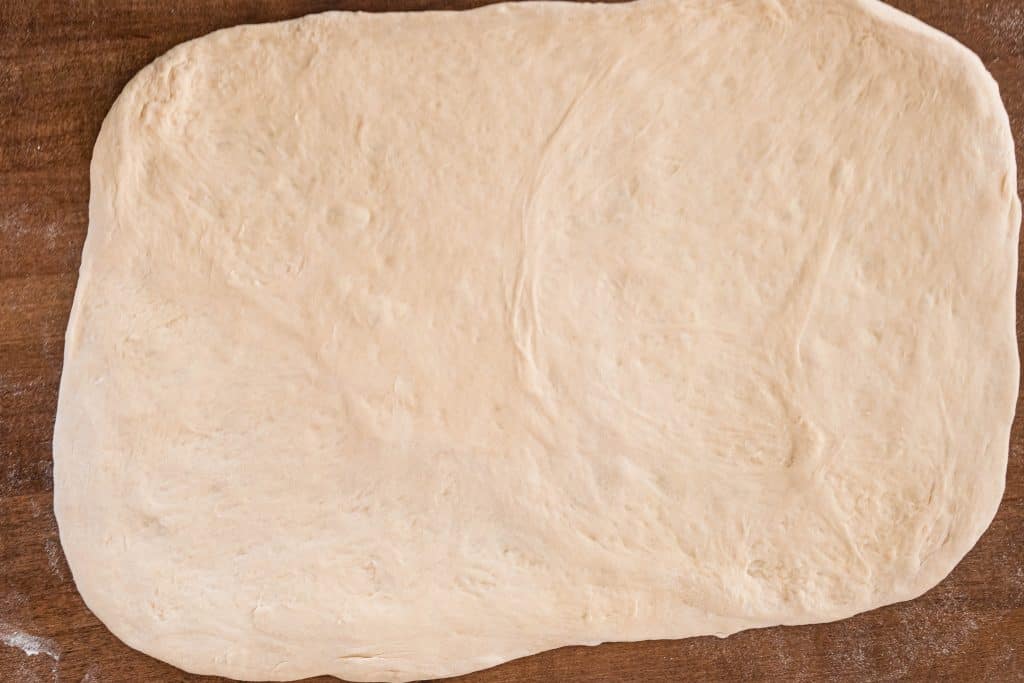 Pizza dough stretched into a rectangle.