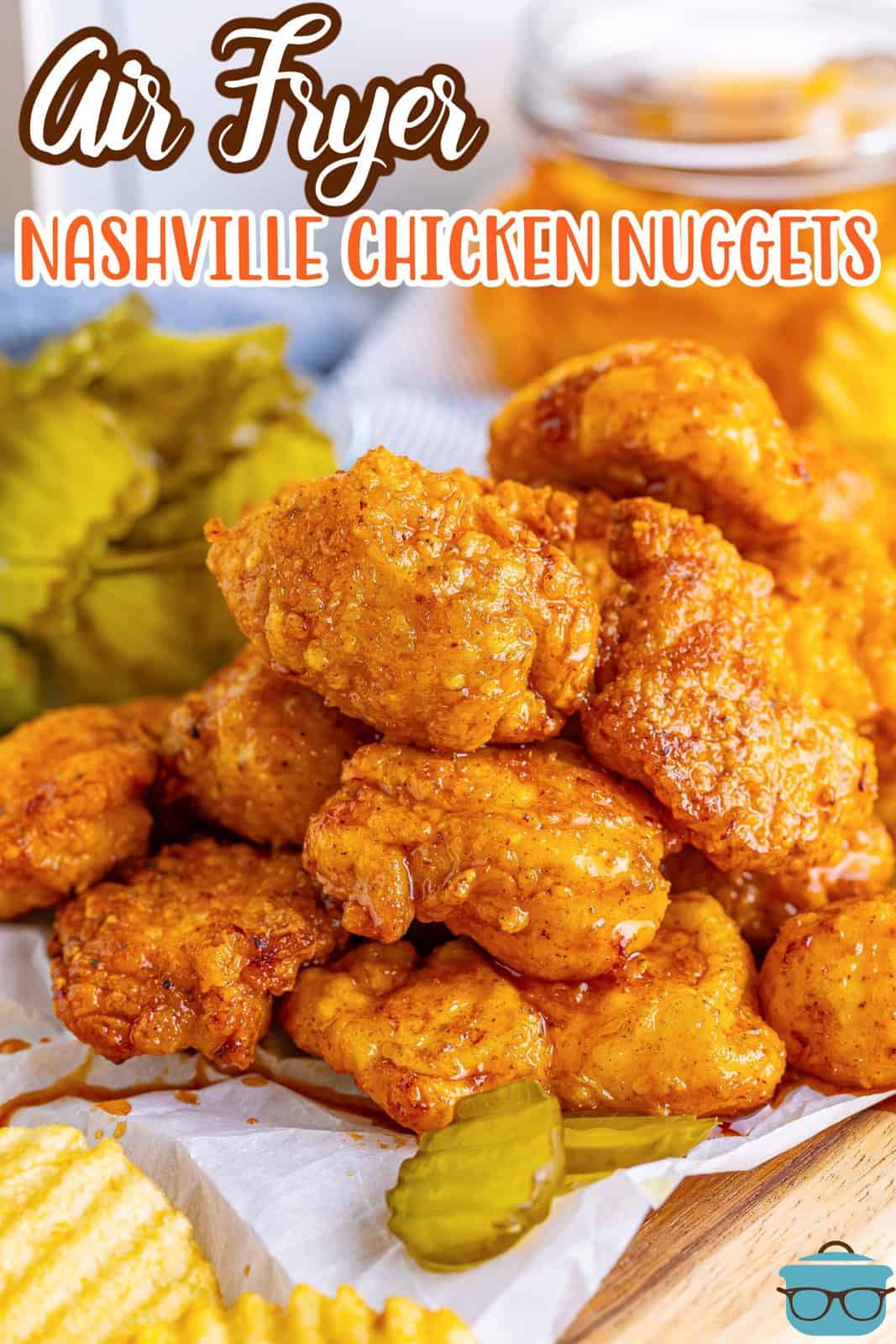 a stack of Nashville Chicken Nuggets with slices of dill pickles and ridge potato chips with a glass of iced tea in the background.