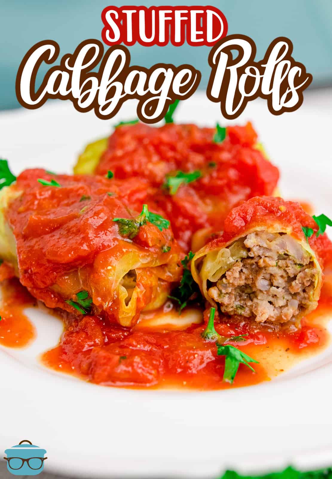 a cabbage roll cut in half to show the inside on a white plate with tomato sauce.