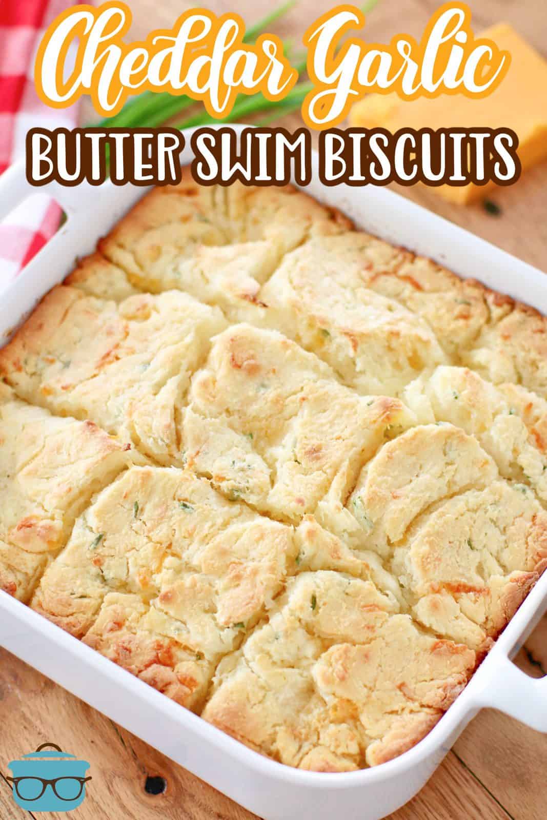 fully baked Cheddar Garlic Butter Dip Biscuits shown in a square white baking dish on a wood surface.