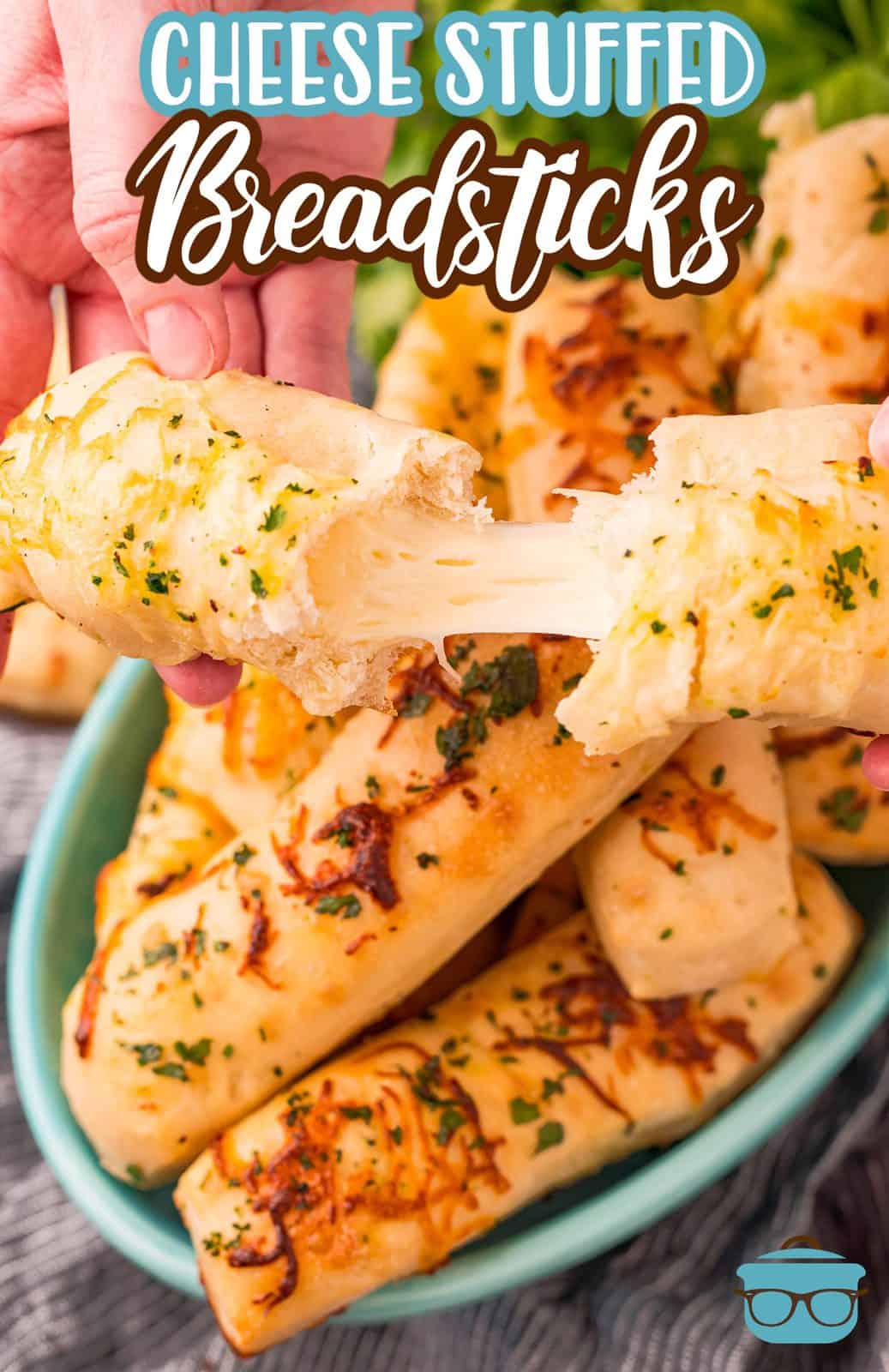 Pinterest image of breadstick pulled apart with cheese pull on top of stacked breadsticks.
