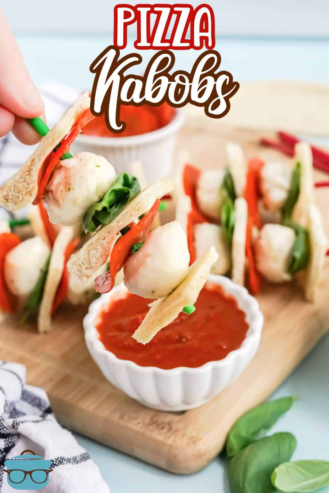 Pinterest image of hand holding Pizza Kabob over bowl of pizza sauce.