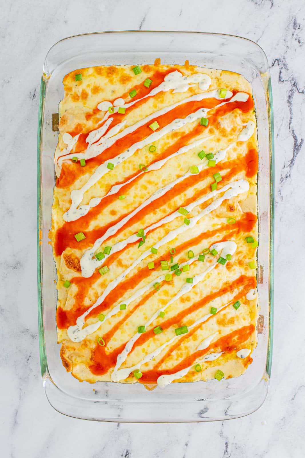Enchiladas topped with buffalo sauce, ranch and green onions.