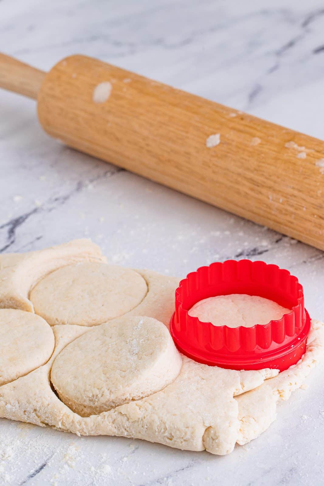 Biscuits being cut out with a biscuit cutter.