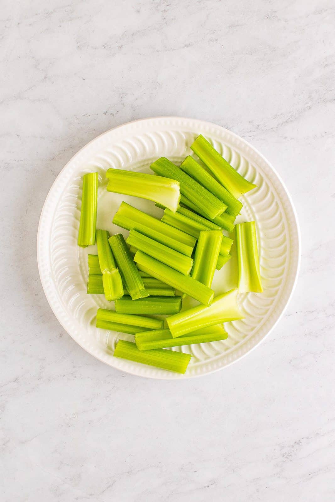 Sliced celery sticks on white plate.