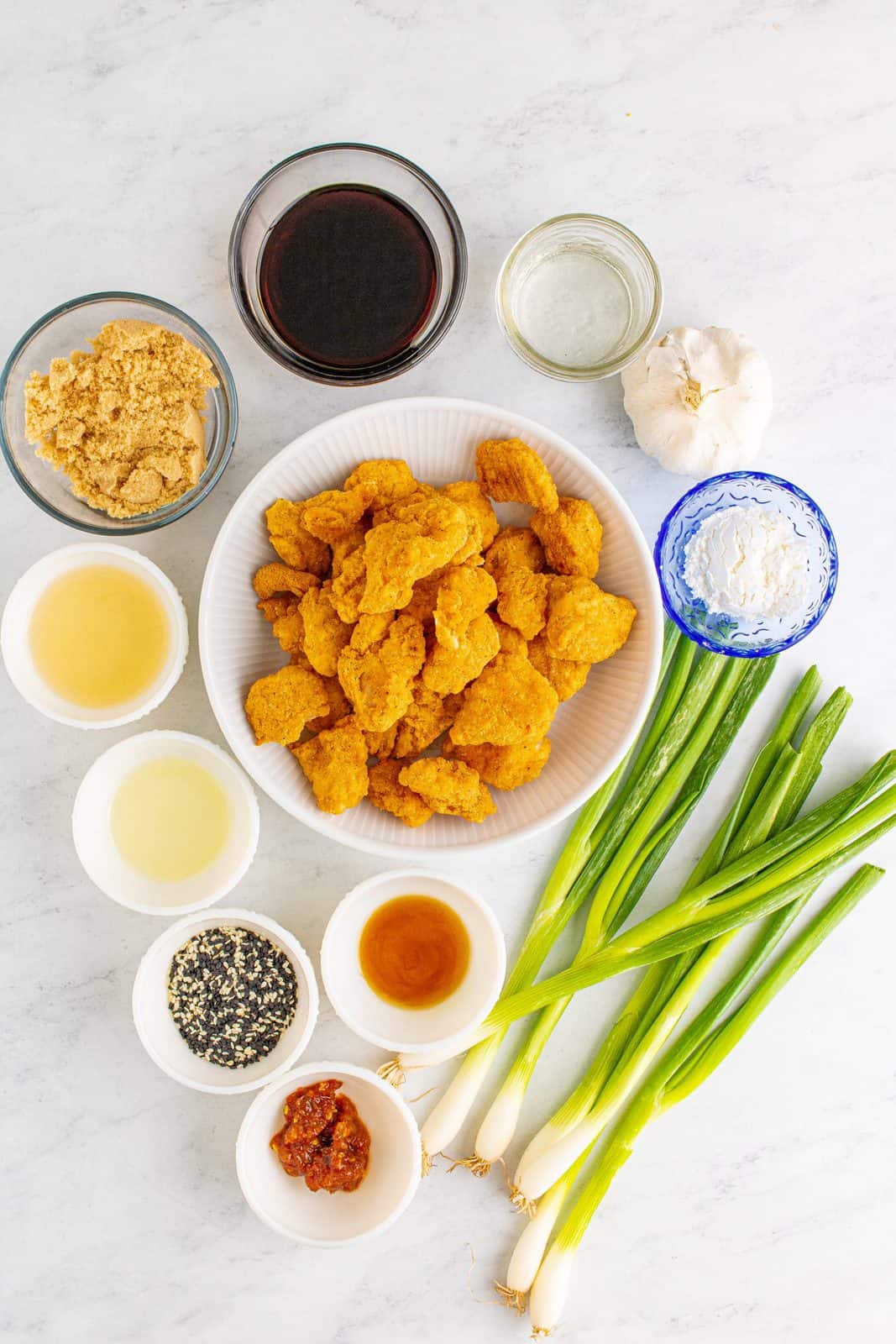 Ingredients needed: light brown sugar, rice wine vinegar, low sodium soy sauce, sesame oil, cooked popcorn chicken, water, cornstarch, vegetable oil, scallions, garlic, chili paste and sesame seeds.