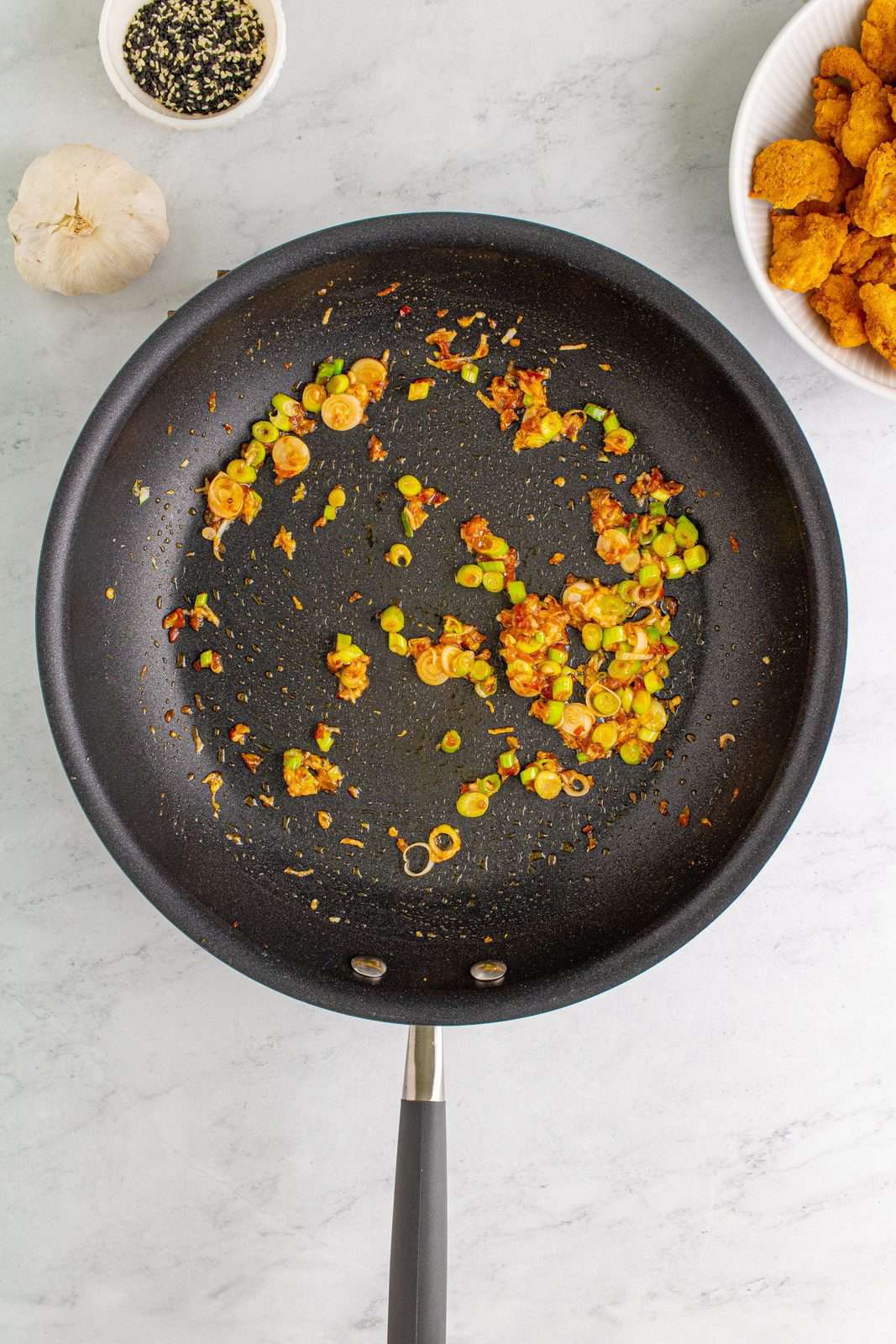 Vegetable oil, scallions, garlic, and chili paste added to skillet and sauteed.