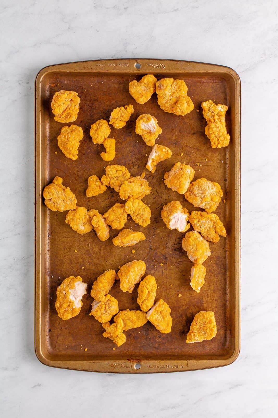 Cooked popcorn chicken on baking sheet.
