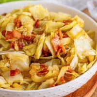 Square image of Bacon Fried Cabbage close up in bowl with serving spoon.