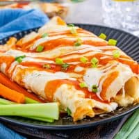Square image of Buffalo Chicken Enchiladas on plate with celery and carrots.