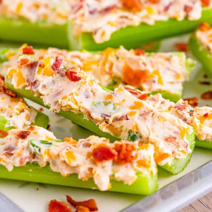 Square close up image of Cheddar Bacon Celery Sticks on white platter.