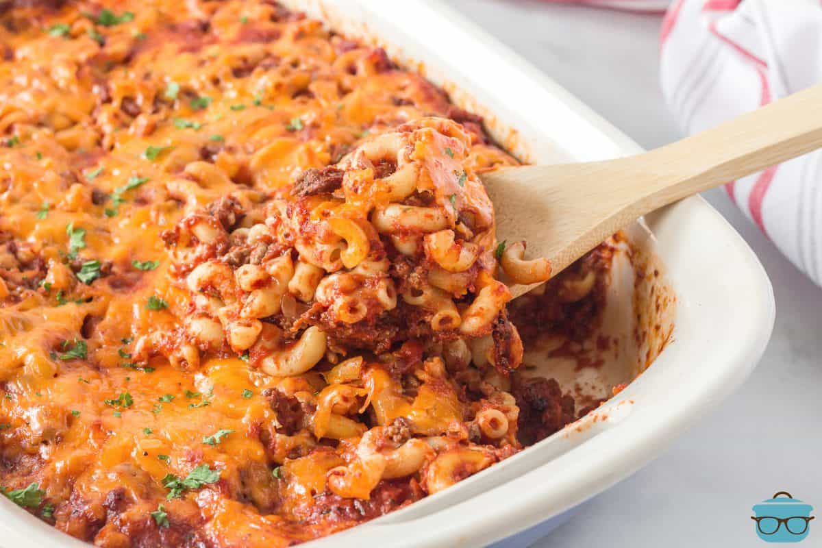 Horizontal picture of Cheeseburger Macaroni Casserole on dish with spoon and some missing.