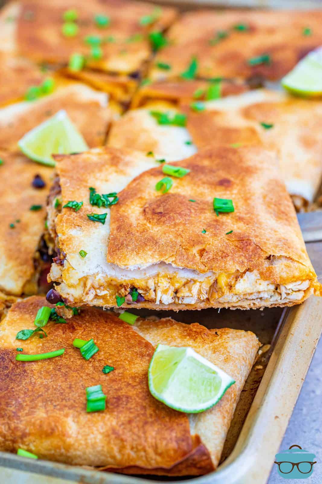 Finished Sheet Pan Chicken Quesadillas with one cut sitting on the pan.